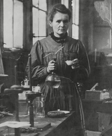 Marie Curie (1867-1934) in haar laboratorium, radioactieve mode uit de geschiedenis, museum, Amsterdam Museum geschreven door Marit Eisses voor Modemuze. Marie Curie, radium, 20e eeuw,  reclamemateriaal voor radioactieve producten, mode, radioactieve mode