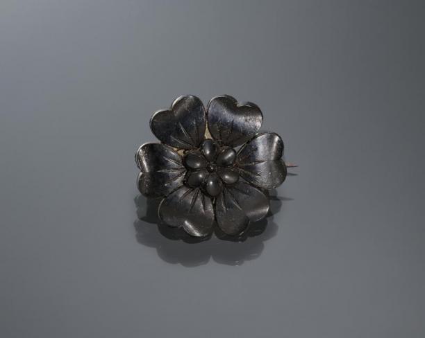 Zwarte broche, gedragen door een vrouw uit Kampen tijdens de zware rouw. De bloem is gemaakt van kunststof, als imitatie van git. Collectie Nederlands Openluchtmuseum.